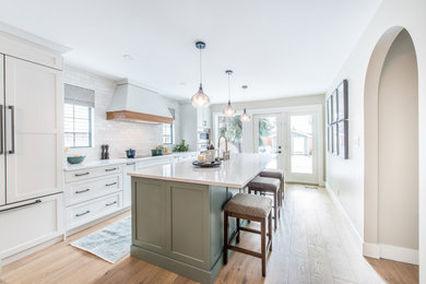 Eat-in kitchen - scandinavian medium tone wood floor eat-in kitchen idea in Edmonton with an undermount sink, shaker cabinets, white cabinets, quartz countertops, white backsplash, subway tile backsplash, white appliances, an island and white countertops