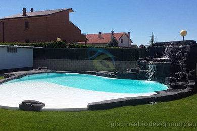 Diseño de piscina con fuente elevada mediterránea de tamaño medio redondeada en patio con losas de hormigón