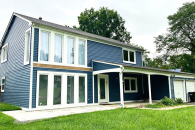 Large contemporary blue two-story vinyl and clapboard house exterior idea in New York with a black roof