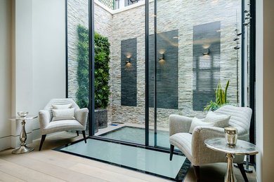 This is an example of a mid-sized contemporary partial sun garden in London with natural stone pavers.