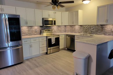Eat-in kitchen - small cottage u-shaped vinyl floor and gray floor eat-in kitchen idea in Columbus with a double-bowl sink, shaker cabinets, white cabinets, granite countertops, gray backsplash, glass tile backsplash, stainless steel appliances, a peninsula and gray countertops