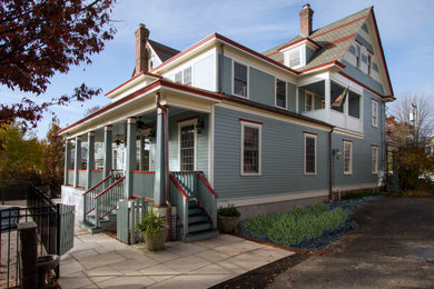 Ejemplo de fachada de casa azul tradicional de dos plantas con revestimiento de aglomerado de cemento, tejado plano, tejado de varios materiales y tablilla