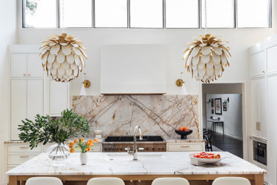 1950s l-shaped medium tone wood floor and vaulted ceiling open concept kitchen photo in Boston with an undermount sink, quartzite countertops, stone slab backsplash, paneled appliances and an island