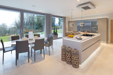 This is an example of a large contemporary l-shaped eat-in kitchen in Oxfordshire with a drop-in sink, flat-panel cabinets, white cabinets, quartzite benchtops, white splashback, glass sheet splashback, black appliances and multiple islands.