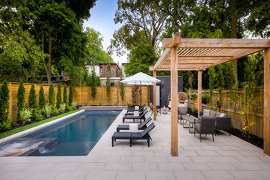 Inspiration for a mid-sized modern partial sun wood fence landscaping in Toronto with a pergola.