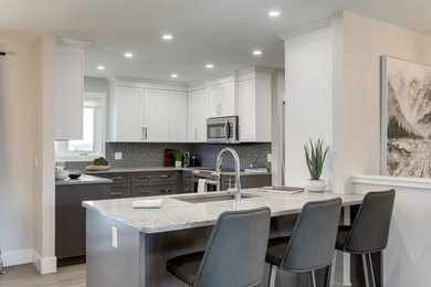 Inspiration for a mid-sized contemporary kitchen in Calgary with a single-bowl sink, shaker cabinets, quartzite benchtops, grey splashback, glass tile splashback, stainless steel appliances, medium hardwood floors, grey floor and grey benchtop.