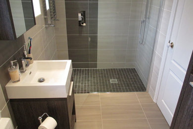 This is an example of a large contemporary kids bathroom in Other with furniture-like cabinets, dark wood cabinets, a two-piece toilet, beige tile, ceramic tile, beige walls, ceramic floors and an integrated sink.