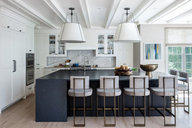Large transitional l-shaped light wood floor, beige floor and exposed beam kitchen photo in Philadelphia with an undermount sink, beaded inset cabinets, white cabinets, quartz countertops, gray backsplash, marble backsplash, paneled appliances, an island and gray countertops