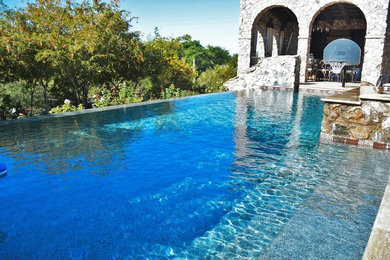 Imagen de piscina con fuente clásica de tamaño medio a medida en patio trasero con adoquines de piedra natural