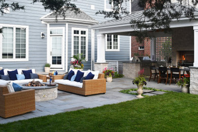 Design ideas for a mid-sized transitional full sun backyard stone and vinyl fence landscaping in Chicago with a fireplace for summer.