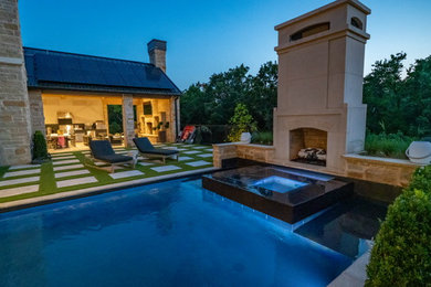 Photo of a large contemporary back rectangular infinity hot tub in Oklahoma City with natural stone paving.