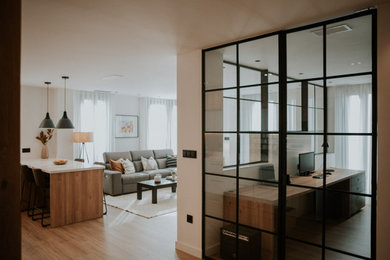 Diseño de sala de estar con biblioteca abierta tradicional renovada grande con paredes blancas, suelo de madera clara, televisor colgado en la pared y suelo beige