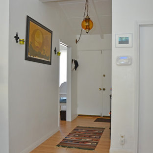 Diseño de hall bohemio, grande, con paredes blancas, suelo laminado, puerta doble, puerta blanca y suelo marrón