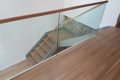Design ideas for a large modern wood l-shaped staircase in Toronto with open risers and glass railing.