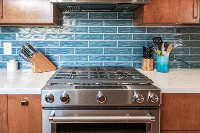 ロサンゼルスにあるお手頃価格の中くらいなミッドセンチュリースタイルのおしゃれなキッチン (フラットパネル扉のキャビネット、中間色木目調キャビネット、クオーツストーンカウンター、青いキッチンパネル、セラミックタイルのキッチンパネル、シルバーの調理設備、アイランドなし、白いキッチンカウンター、ドロップインシンク、淡色無垢フローリング、三角天井) の写真