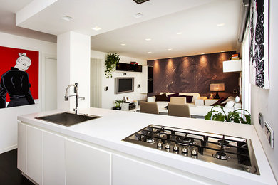 Inspiration for a mid-sized modern open plan kitchen in Turin with a peninsula, a drop-in sink and dark hardwood floors.