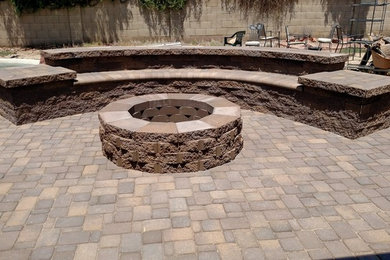 This is an example of a mid-sized traditional backyard full sun xeriscape in Other with natural stone pavers and a fire feature.