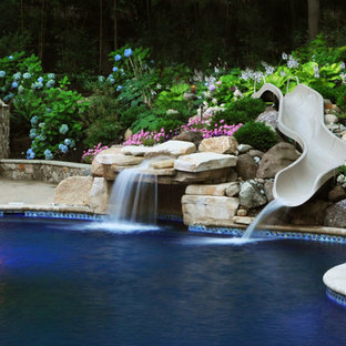 Inspiration för stora klassiska anpassad träningspooler på baksidan av huset, med vattenrutschkana och grus