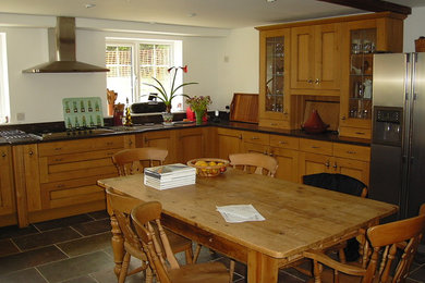 Inspiration for a large farmhouse u-shaped kitchen/diner in Wiltshire with a built-in sink, shaker cabinets, medium wood cabinets, granite worktops, black splashback, stainless steel appliances, slate flooring, no island and green floors.