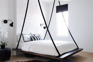 Inspiration for a mid-sized contemporary bedroom in Chicago with white walls, light hardwood floors and no fireplace.