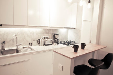 Réalisation d'une petite cuisine américaine minimaliste en L avec un évier encastré, un placard à porte affleurante, plan de travail en marbre, une crédence en marbre, un électroménager en acier inoxydable, un sol en marbre et un plan de travail blanc.