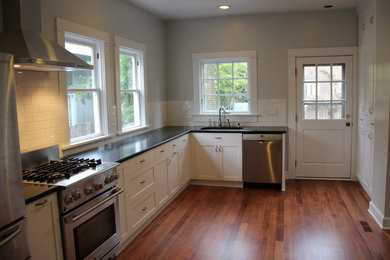 Mid-sized elegant l-shaped medium tone wood floor enclosed kitchen photo in Portland with an undermount sink, shaker cabinets, white cabinets, quartz countertops, white backsplash, subway tile backsplash, stainless steel appliances and no island
