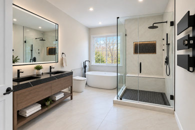 Inspiration for a mid-sized modern master porcelain tile, beige floor, double-sink and vaulted ceiling bathroom remodel in DC Metro with flat-panel cabinets, brown cabinets, a bidet, white walls, quartz countertops, black countertops, a niche and a freestanding vanity