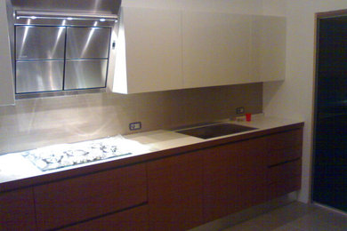 Photo of a modern kitchen in Other with a single-bowl sink, flat-panel cabinets, laminate benchtops, beige splashback, porcelain splashback, stainless steel appliances and porcelain floors.