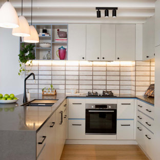Mid-sized industrial u-shaped open plan kitchen in Brisbane with a double-bowl sink, flat-panel cabinets, white cabinets, quartz benchtops, grey splashback, cement tile splashback, stainless steel appliances, light hardwood floors, no island, brown floor, black benchtop and exposed beam.