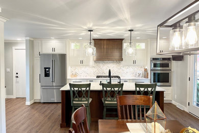 Large transitional u-shaped medium tone wood floor and brown floor open concept kitchen photo in Other with an undermount sink, flat-panel cabinets, white cabinets, quartz countertops, multicolored backsplash, stone tile backsplash, stainless steel appliances, an island and white countertops