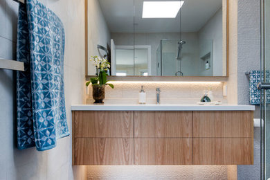 Design ideas for a mid-sized contemporary master bathroom in Melbourne with furniture-like cabinets, medium wood cabinets, a curbless shower, a wall-mount toilet, white tile, porcelain tile, white walls, porcelain floors, an undermount sink, engineered quartz benchtops, blue floor and a hinged shower door.