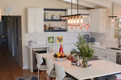 Mid-sized country l-shaped eat-in kitchen in Denver with an undermount sink, recessed-panel cabinets, white cabinets, quartz benchtops, white splashback, ceramic splashback, stainless steel appliances, medium hardwood floors, with island, brown floor and white benchtop.
