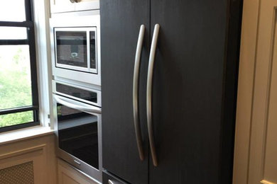 Inspiration for a transitional u-shaped medium tone wood floor enclosed kitchen remodel in New York with an undermount sink, shaker cabinets, white cabinets, quartz countertops, blue backsplash, glass tile backsplash and stainless steel appliances