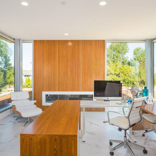 Inspiration for a large modern home office and library in Vancouver with white walls, porcelain flooring, a ribbon fireplace, a wooden fireplace surround, a freestanding desk and white floors.