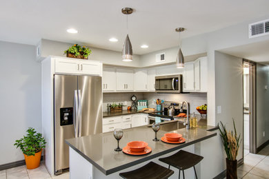 Inspiration for a mid-sized transitional u-shaped porcelain tile and beige floor eat-in kitchen remodel in Phoenix with an undermount sink, shaker cabinets, white cabinets, quartz countertops, gray backsplash, subway tile backsplash, stainless steel appliances, a peninsula and gray countertops