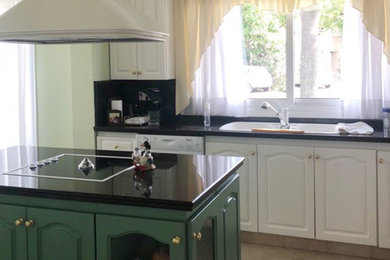 Medium sized traditional l-shaped kitchen/diner in Berkshire with a double-bowl sink, shaker cabinets, white cabinets, marble worktops, black splashback, marble splashback, integrated appliances, ceramic flooring, an island, beige floors and black worktops.