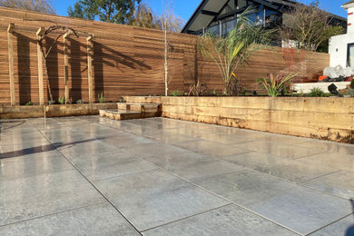 Foto de jardín mediterráneo grande en verano en patio trasero con macetero elevado, exposición parcial al sol, adoquines de piedra natural y con madera