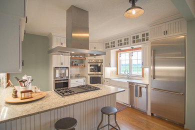 L-shaped medium tone wood floor eat-in kitchen photo in Cedar Rapids with white backsplash, stainless steel appliances, a farmhouse sink, louvered cabinets, white cabinets, marble countertops, subway tile backsplash and a peninsula