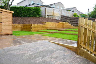 Inspiration for a medium sized rural back formal partial sun garden for spring in Glasgow with a retaining wall, natural stone paving and a wood fence.