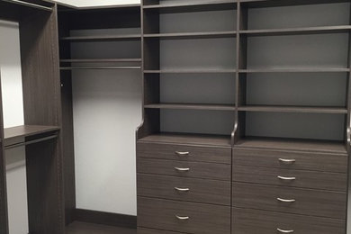 Mid-sized modern gender-neutral walk-in wardrobe in Miami with open cabinets, dark wood cabinets and carpet.