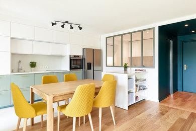Cette image montre une grande cuisine ouverte linéaire design avec un évier encastré, un plan de travail en quartz, une crédence blanche, un électroménager en acier inoxydable, parquet clair, îlot, un sol marron et un plan de travail blanc.