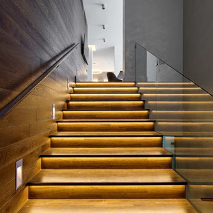 На фото: прямая лестница в современном стиле с стеклянными перилами с