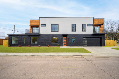 Modern black two-story stucco and board and batten house exterior idea in Dallas with a shingle roof and a black roof