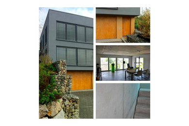 Mittelgroßes, Zweistöckiges Modernes Haus mit Betonfassade, grauer Fassadenfarbe und Flachdach in Sonstige