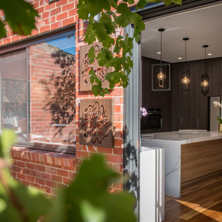 Idéer för mellanstora eklektiska foajéer, med röda väggar, mörkt trägolv, en skjutdörr, en grå dörr och brunt golv