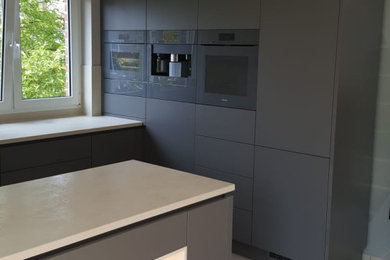 Offene, Mittelgroße Moderne Küche in U-Form mit Waschbecken, flächenbündigen Schrankfronten, grauen Schränken, Arbeitsplatte aus Fliesen, Küchenrückwand in Beige, Rückwand aus Keramikfliesen, Elektrogeräten mit Frontblende, Porzellan-Bodenfliesen, Halbinsel, grauem Boden und beiger Arbeitsplatte in Berlin