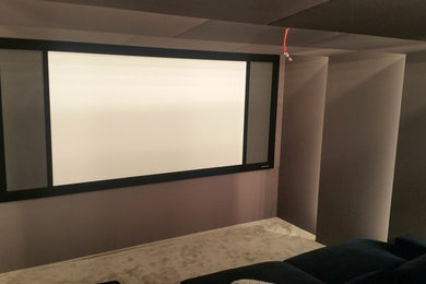 Expansive modern enclosed home cinema in London with white walls and a projector screen.