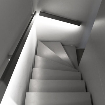 Graue Treppe mit schwarzem Handlauf mit integrierter, indirekter Beleuchtung