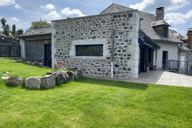 Modelo de fachada de casa bifamiliar gris y gris campestre de tamaño medio de tres plantas con revestimiento de piedra y tejado de teja de barro