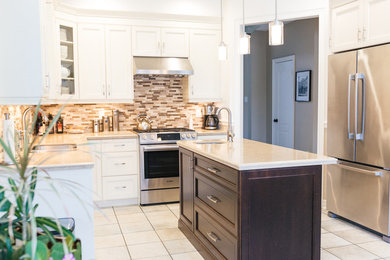 Mid-sized elegant u-shaped ceramic tile enclosed kitchen photo in Toronto with a double-bowl sink, white cabinets, granite countertops, brown backsplash, glass tile backsplash, stainless steel appliances, an island and beaded inset cabinets